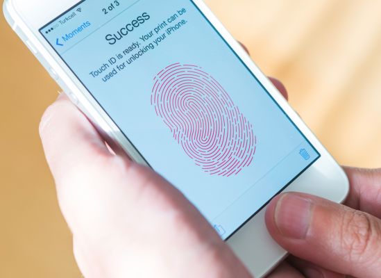 Picture of someone using their thumb print to unlock their phone.