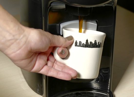 Person serving themselves a cup from a self-serve machine.