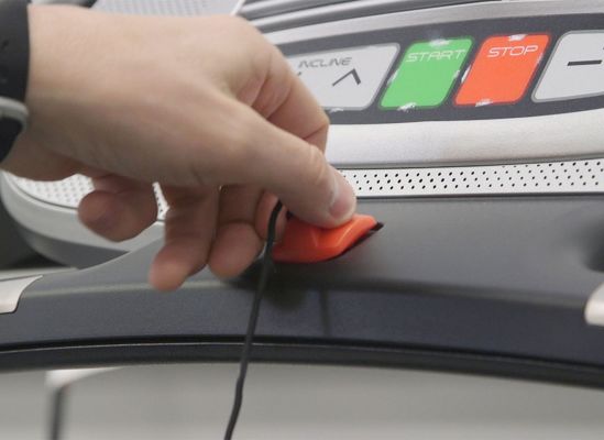A persn holding the tether safety key on a treadmill.