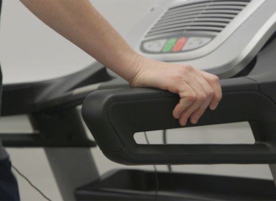 a person using the hand rails on a treadmill.