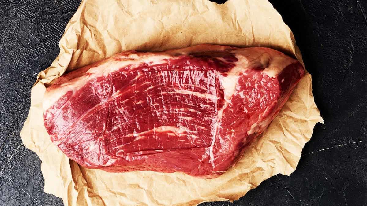 A photograph of a whole cut of beef resting on brown paper.