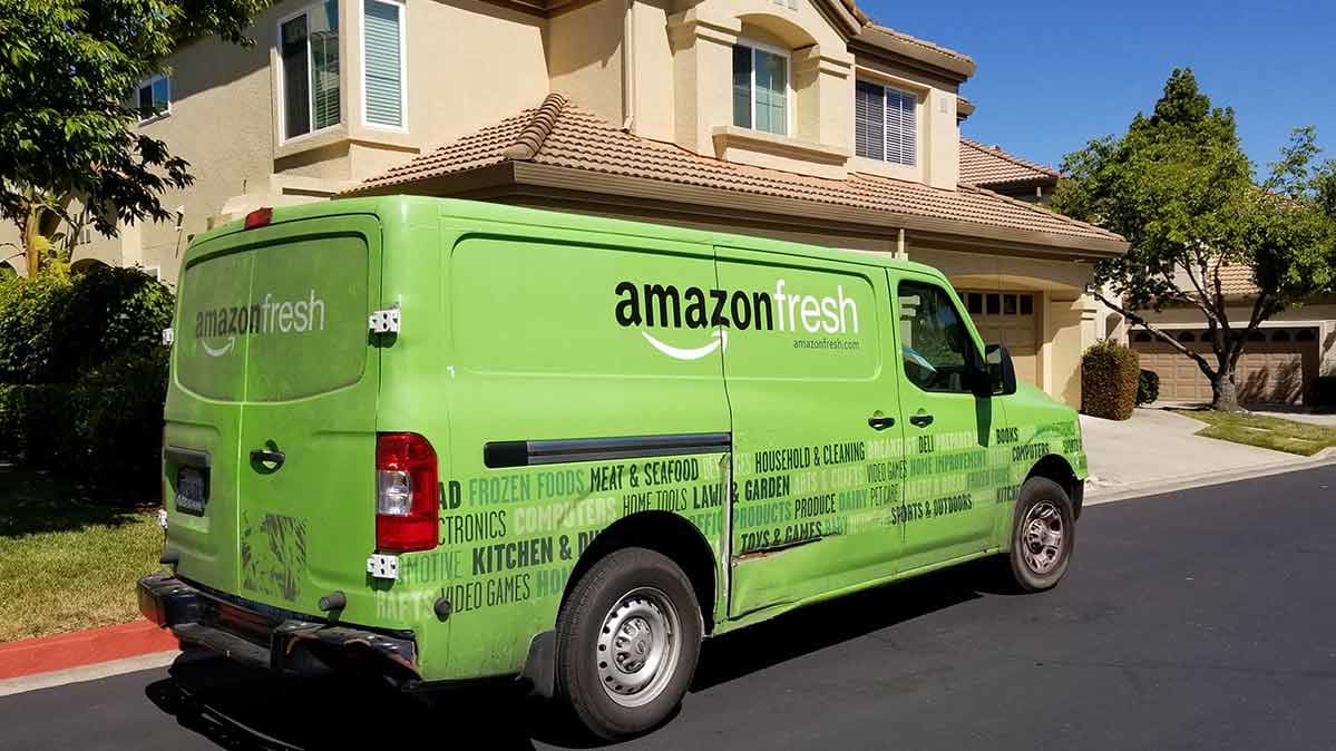 An AmazonFresh delivery truck in front of a house