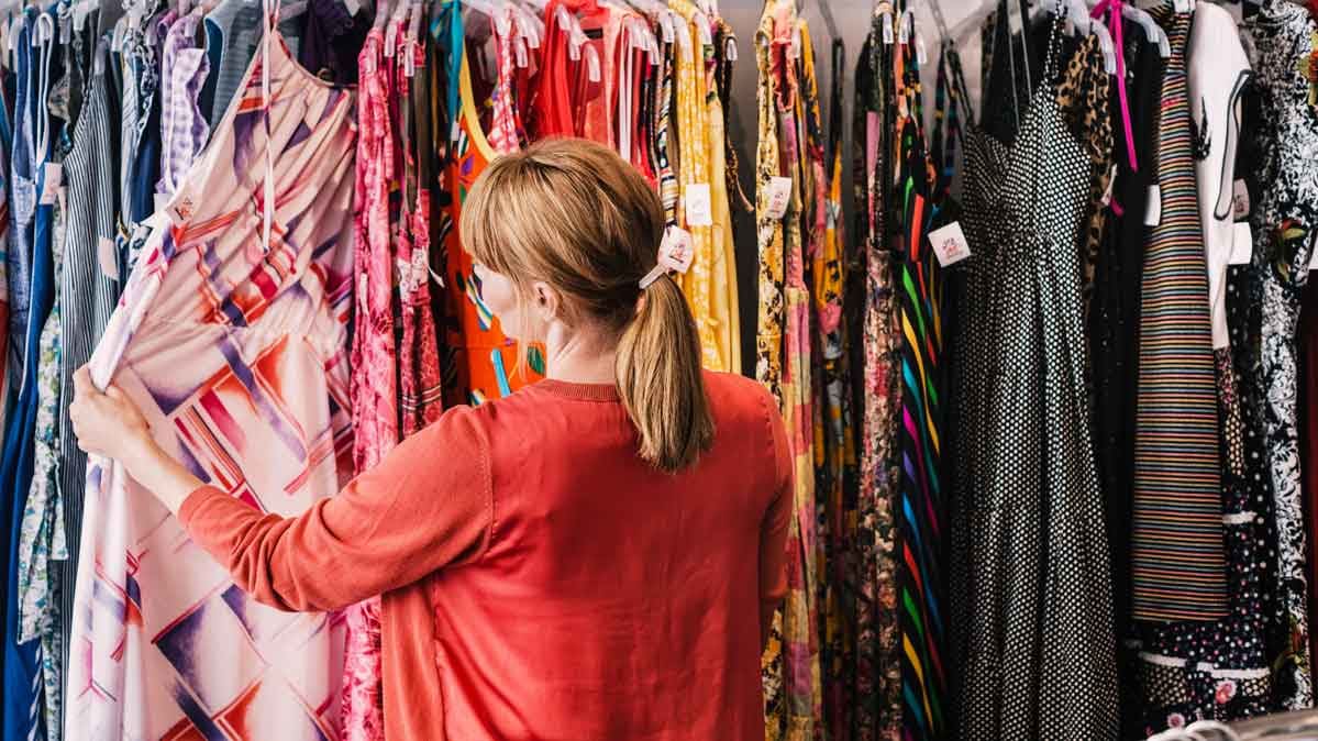 College-age woman looking at clothing in a store.