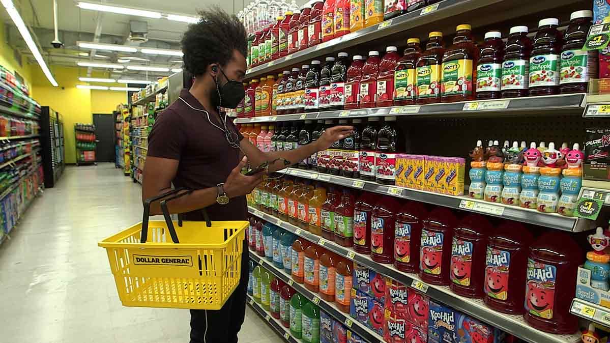 A man stands in a grocery aisle examining nutrition labels.