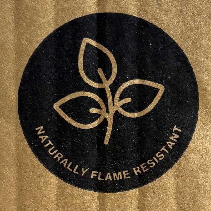 Box packaging that has a leaf symbol within a circle and says "Naturally Flame Resistant".