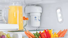 GE MWF water filter in a refrigerator next to a jug of orange juice.