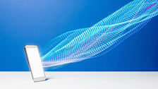 Streams of data flowing from brightly lit smart phone on white shelf