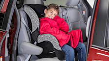 Child in car seat wearing winter coat on top of harness