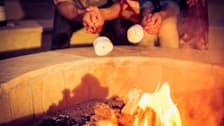2 people roasting marshmallows at backyard fire pit
