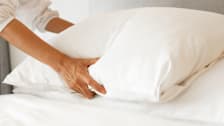 Hands holding pillow in bedroom