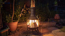 A chiminea seen lit in a backyard at night