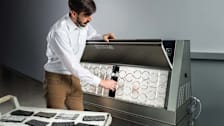 Technician looking at Accelerated Weathering Tester with cart of shingle samples nearby