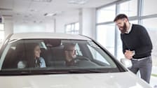 couple buying a new car at a car dealership and  talking to a car salesman