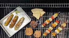 A variety of plant-based foods being cooked on a gas grill