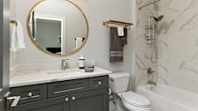 small bathroom with under the sink cabinet and large round mirror above sink