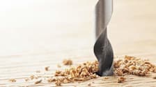 A close-up of a drill bit going into a piece of wood