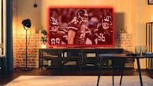 television with football game glowing red in an empty living room