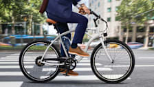 person in blue suit riding electric bike through city street with crosswalk