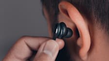 detail of person putting earbud into ear