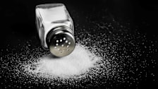 spilled glass salt shaker on black background