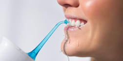 person using a water flosser