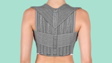 backside of person's toro showing them wearing a grey posture correcting device