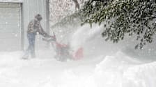 Person using snow blower in the middle of a snow storm.
