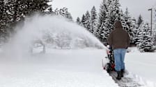 Person creating a path through snow using a snowblower