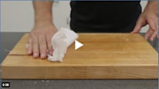 Person cleaning a wooden cutting board
