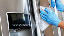 Person wiping refrigerator with gloves on
