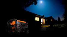 Generac XT8500EFI in front of home at night with moon above and lights on in the house