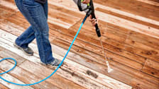 detail of person using pressure washer to clean wood decking