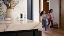 Ring Indoor Security Camera on kitchen counter next to utensil holder—two kids are playing with a ball in the background