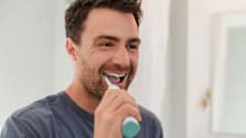 Person brushing their teeth with an electric toothbrush