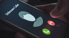 detail of hand holding smartphone with Unknown Caller on screen