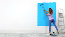 Woman painting a wall blue