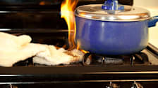 Dishtowel on fire next to pot on gas stove