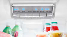 detail of temperature control panel of refrigerator with bottles of juice blurred below it