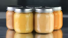 group of 5 glass jars of baby food on metal surface