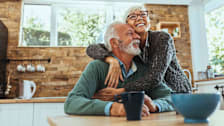 A smiling older couple in their kitchen at home