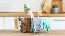 A basket of cleaning products on a kitchen counter