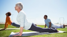 Seniors practicing yoga in sunny beach park