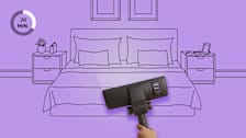 Hand vacuuming mattress in bedroom setting with purple background