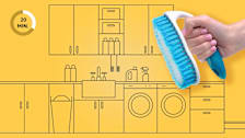 Hand holding a cleaning brush in front of an illustration of a laundry room.