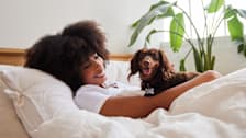 Smiling young woman in bed with her dachshun