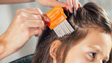 Parent combing their child's hair using a lice nit comb