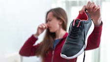 Woman holding nose from smell from sweaty running shoes she is holding