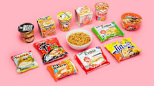 packages of instant ramen surrounding a bowl of noodles on a pink background