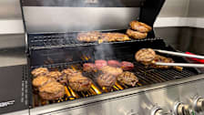 Filet mignons and ribeyes cooking on a grill