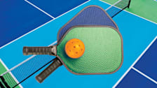 pickleball rackets and ball with pickleball court in background